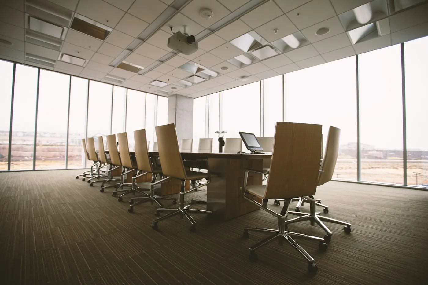 Empty corporate boardroom with a long table and city views