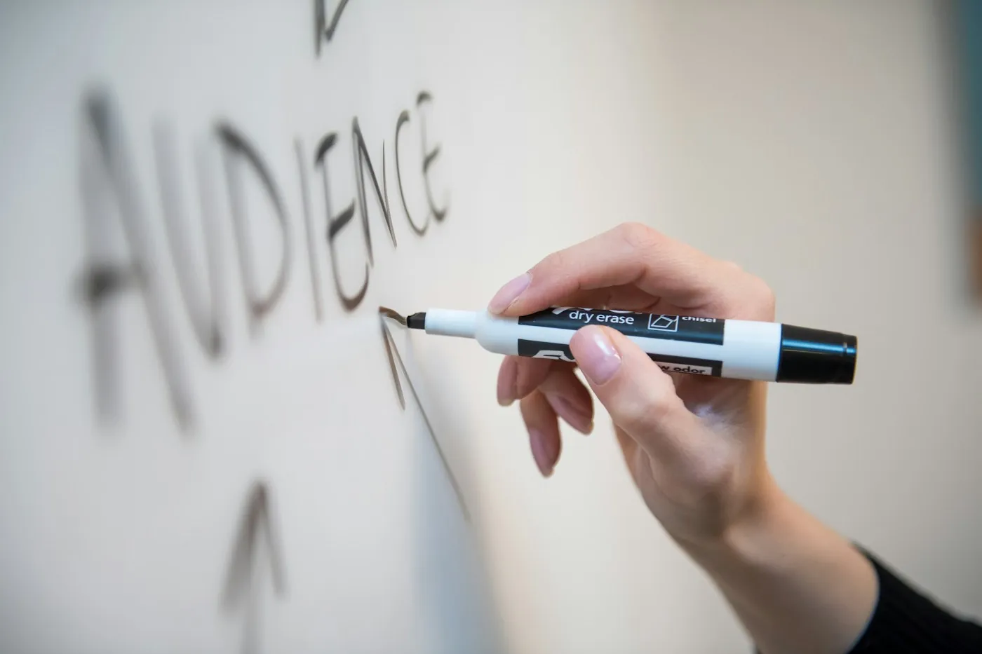 Hand writing the word audience on a whiteboard during a content workshop