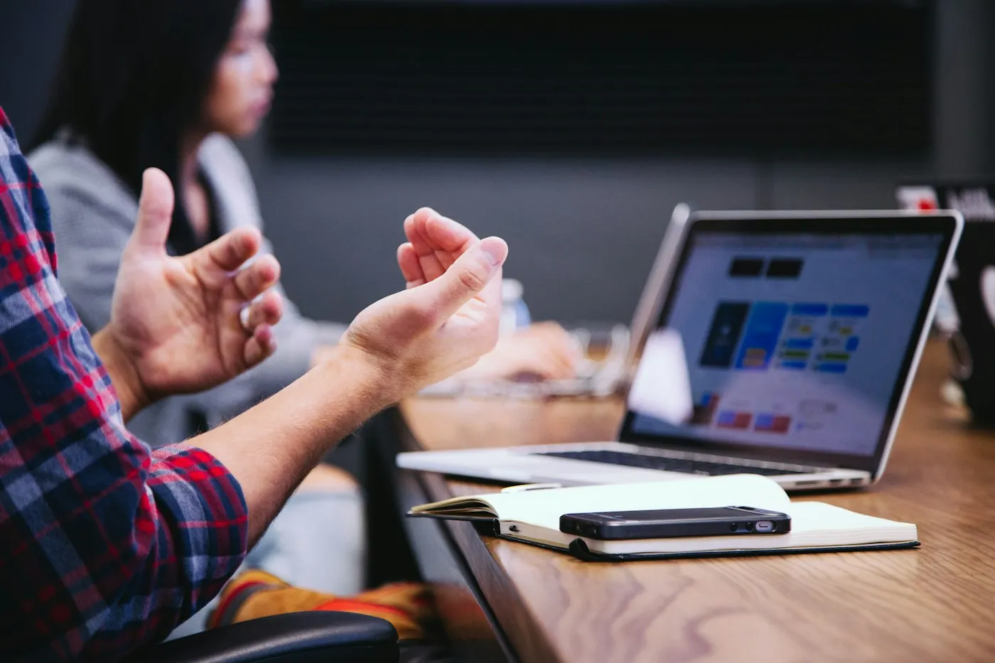 Team member explaining a plan during a meeting with a laptop open