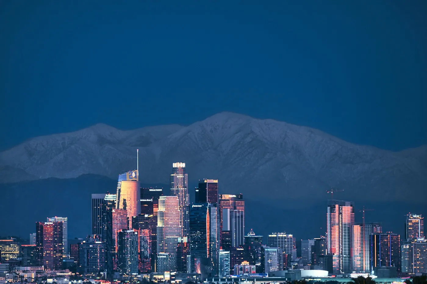 Los Angeles towers lit at night beneath the San Gabriel Mountains