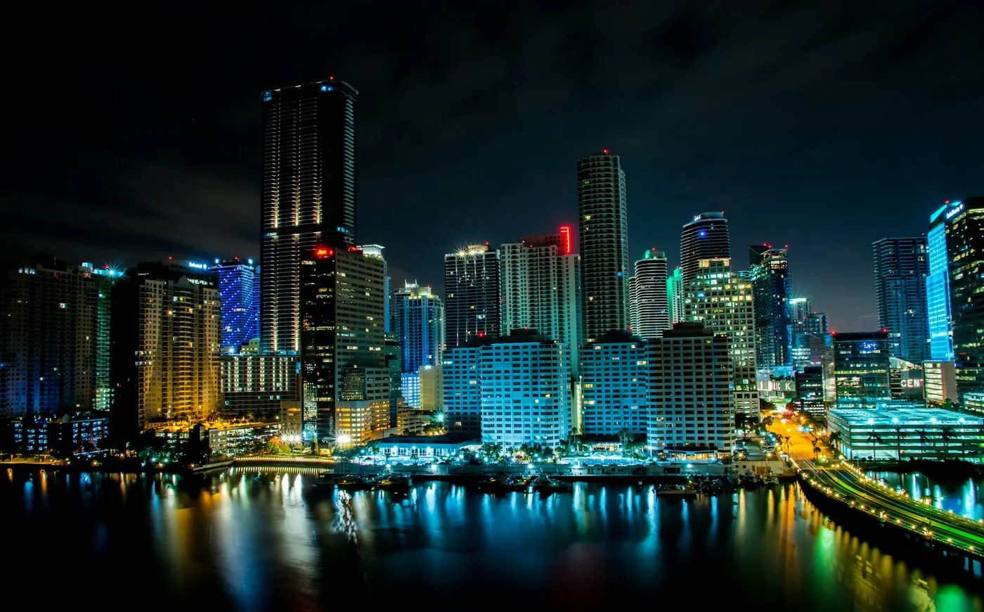 Miami waterfront towers glowing at night with reflections on Biscayne Bay