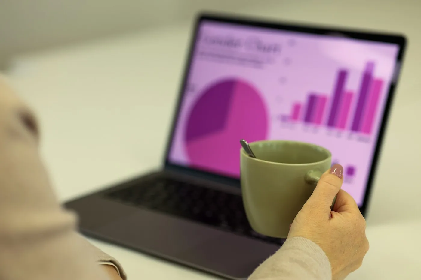 Revenue chart in violet tones on a laptop beside a coffee cup