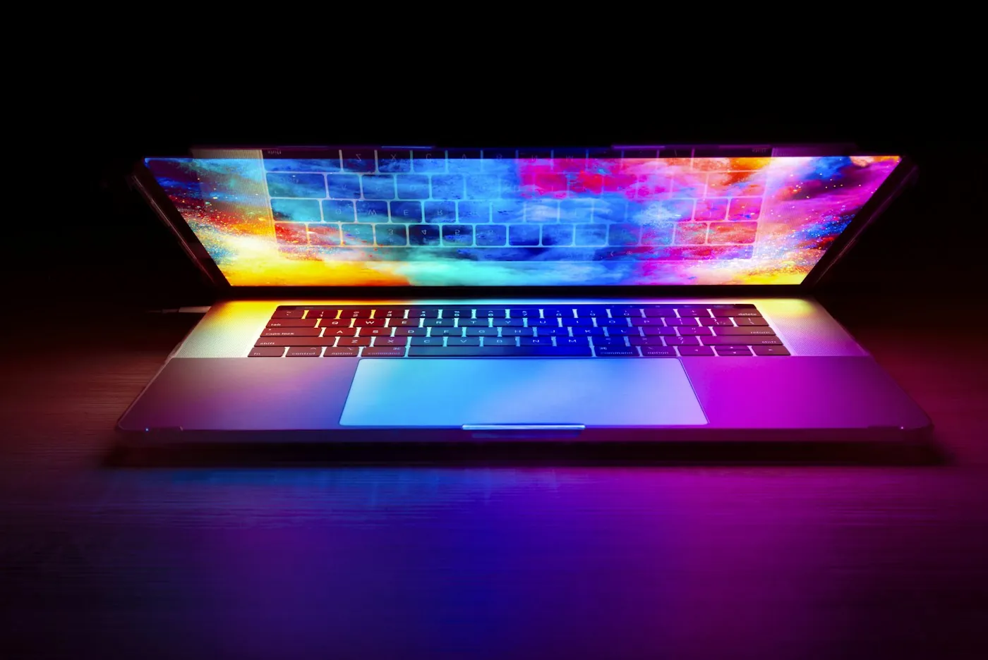 Open laptop glowing with color in a dark room