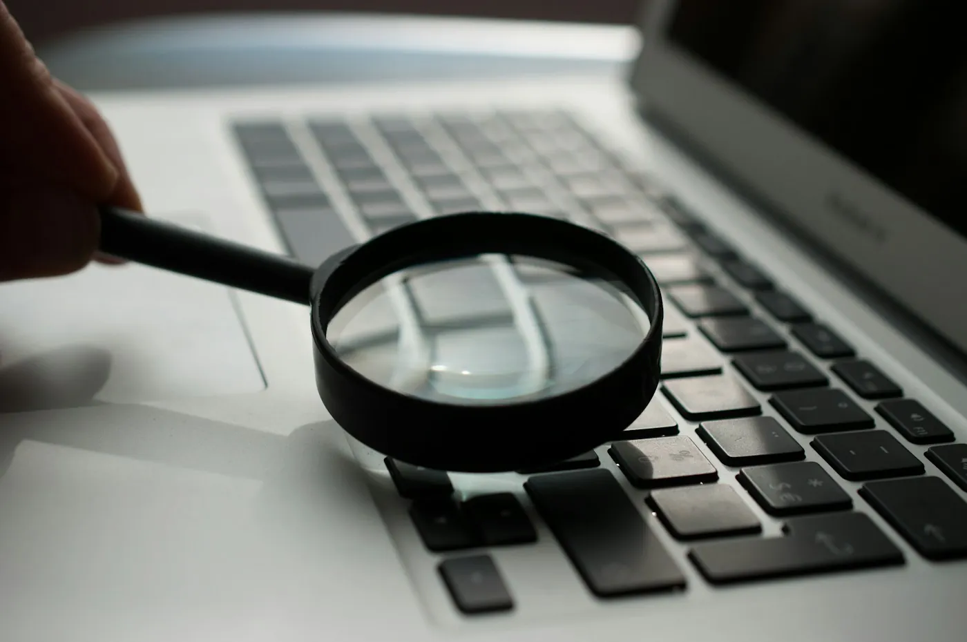 Magnifying glass resting on a laptop keyboard