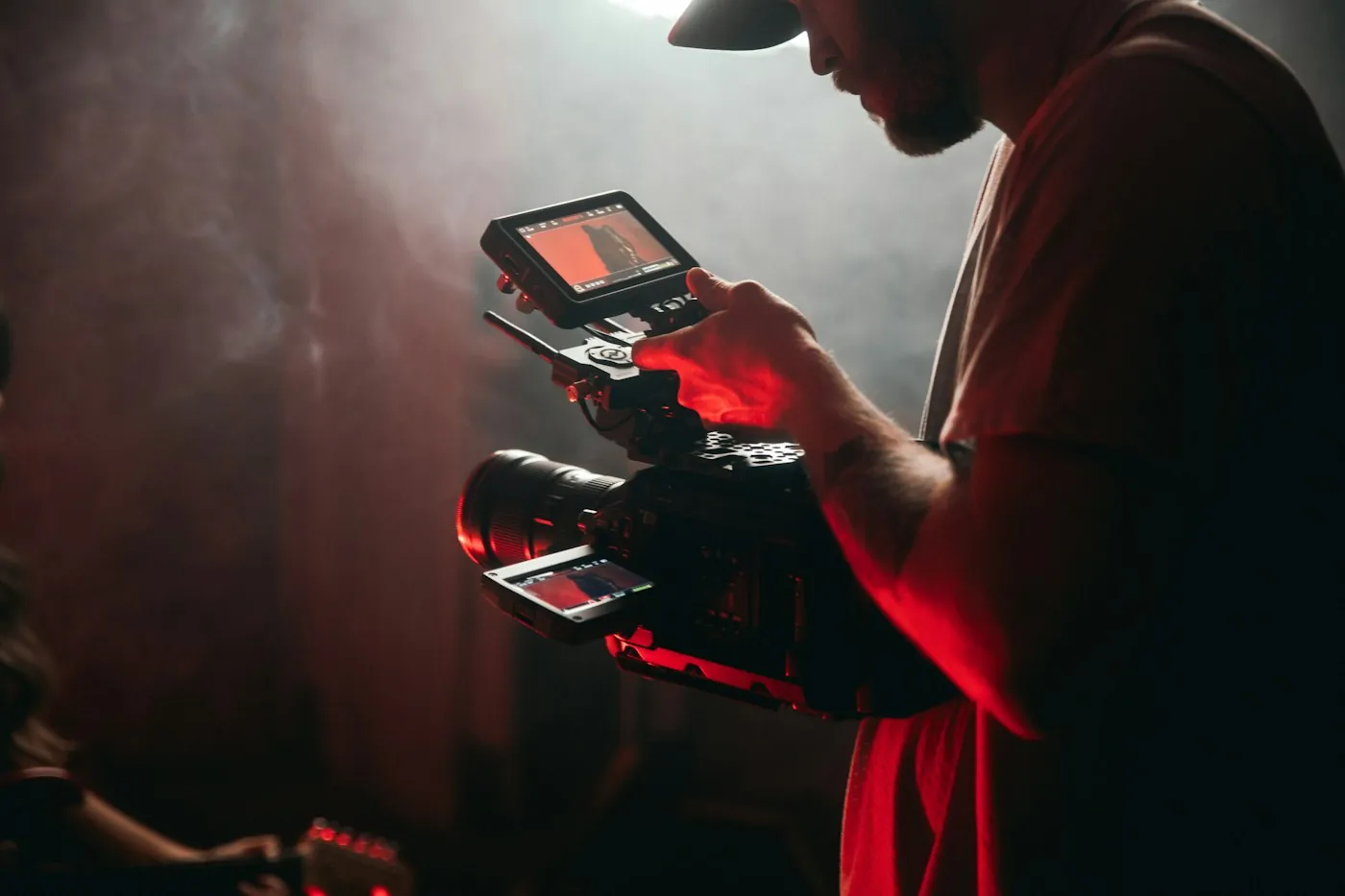 Camera operator filming with a cinema rig in a dark studio