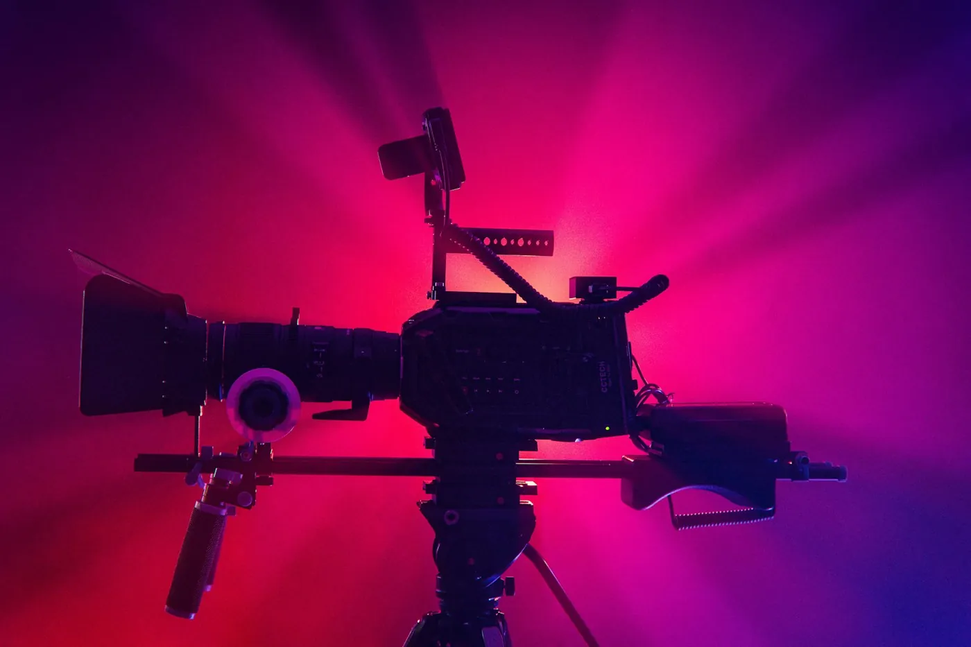 Cinema camera silhouetted against violet and magenta stage light